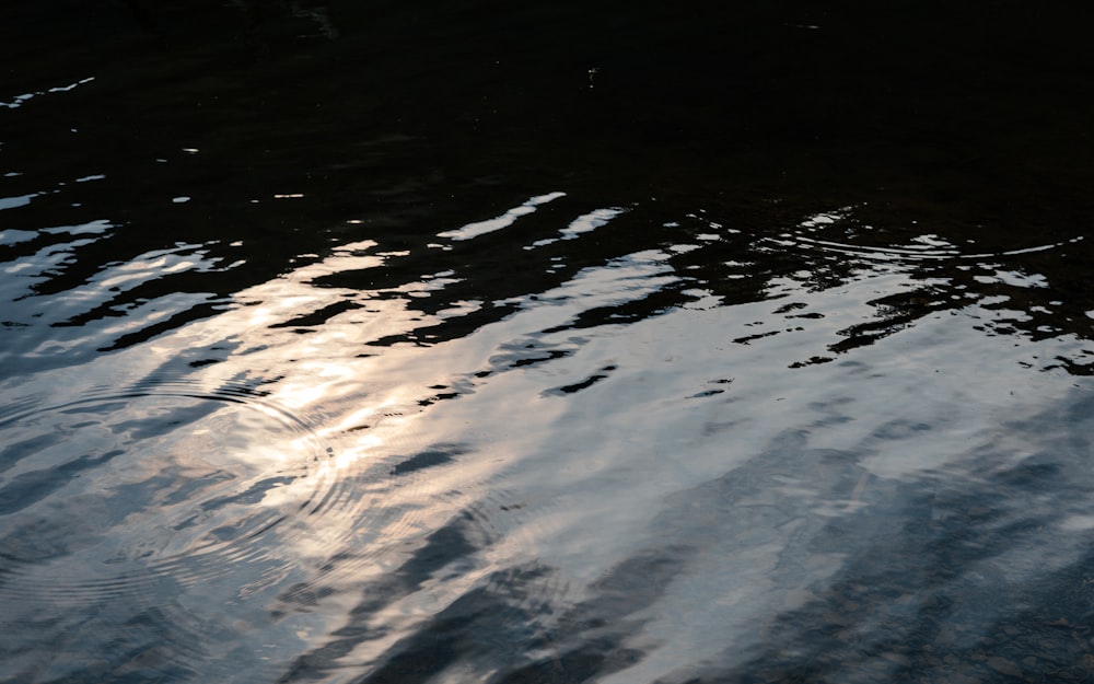 the water is reflecting the sky and clouds