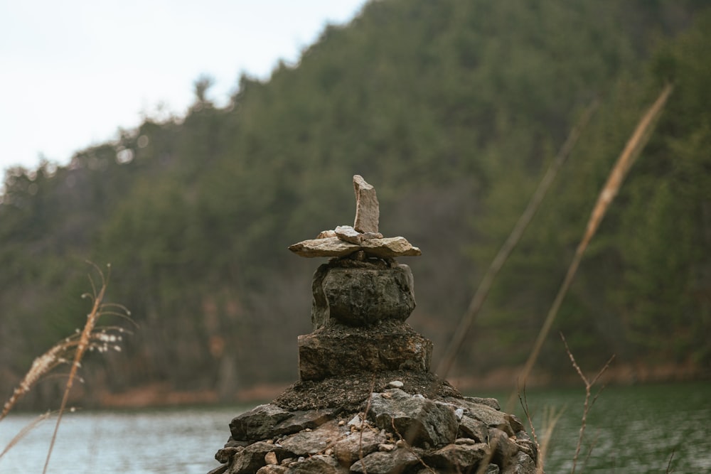 a stone cross sitting on top of a rock next to a body of water