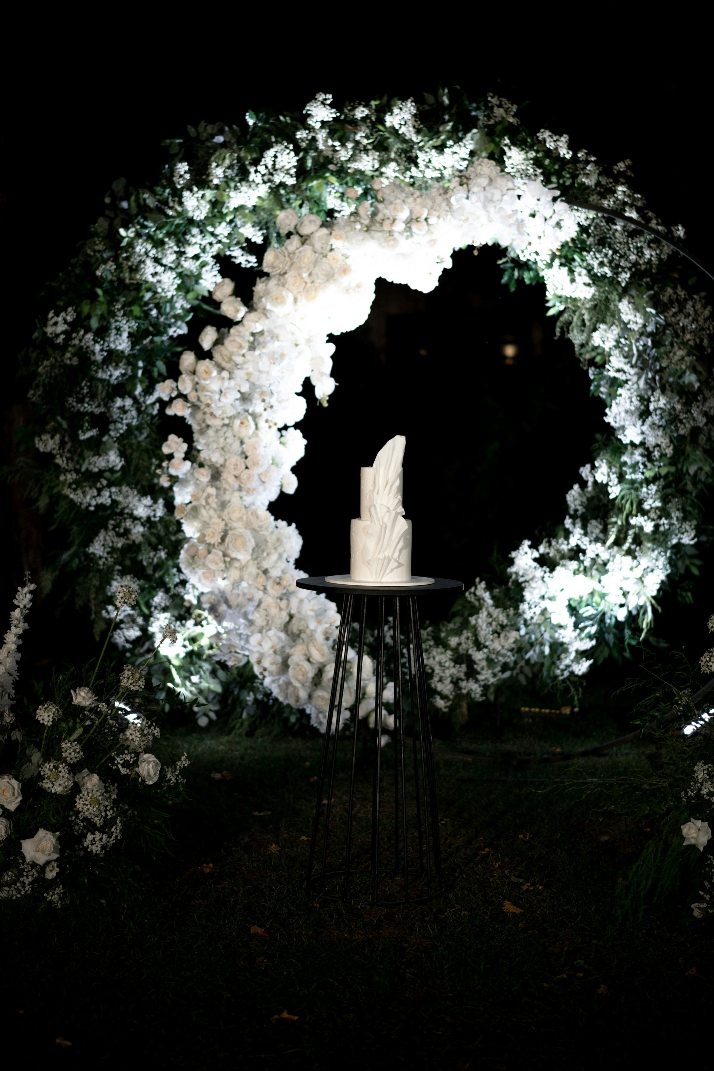Full wedding cake display on marble pedestal in elegant venue setting