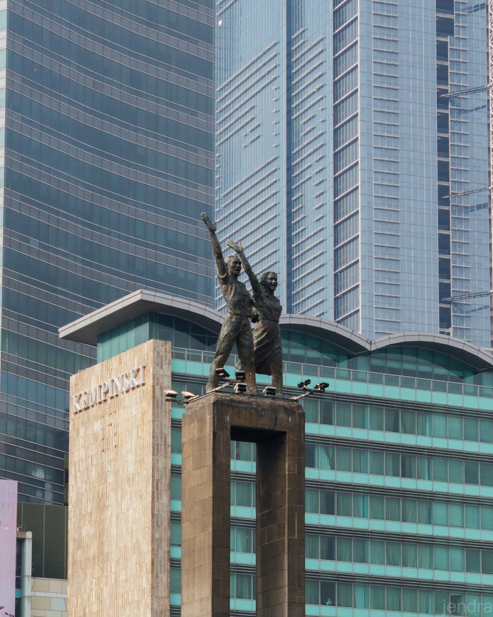 a statue of two men on a pedestal in front of tall buildings