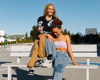 two women sitting on a bench in a parking lot