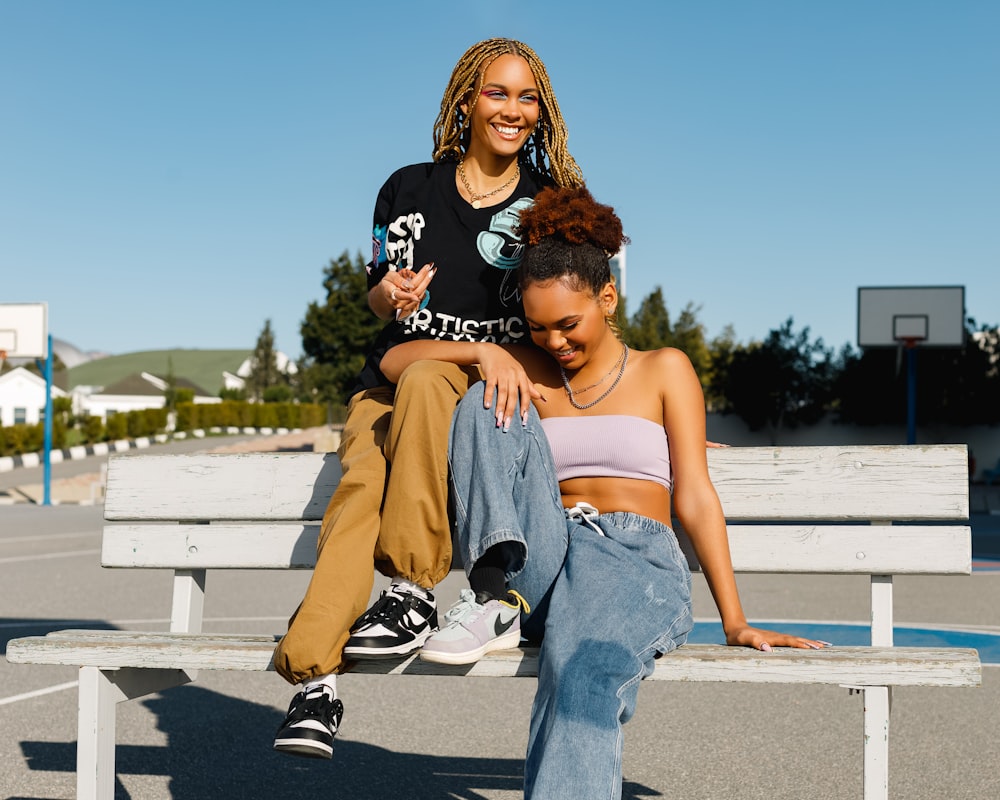 two women sitting on a bench in a parking lot