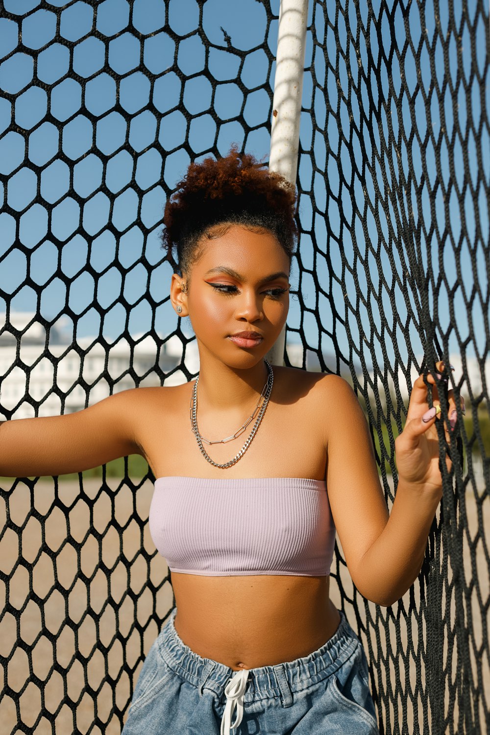 a woman leaning against a fence with a tennis racket