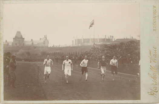 A vintage black-and-white photo of Leon W Hawker mid-run during a track event, capturing his determination and athletic spirit.