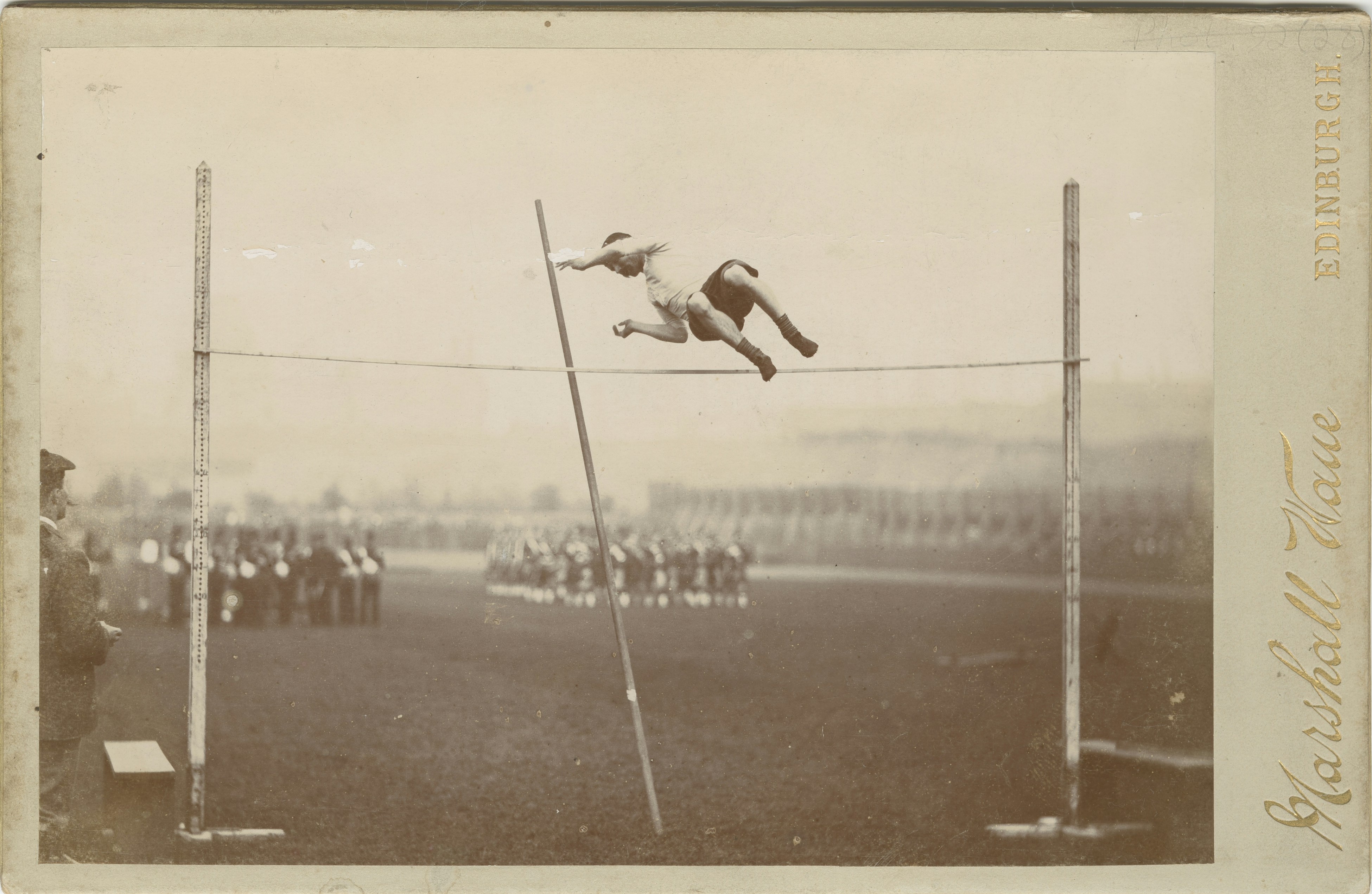 an old photo of a man jumping over a high jump