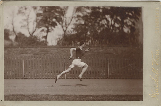 A vintage black-and-white photo of Leon W Hawker mid-run during a track event, capturing his determination and athletic spirit.