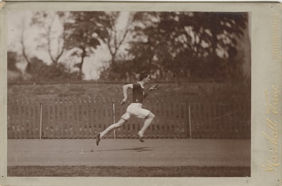 Black and white photo of a runner in mid-stride on a city street, minimal background.