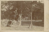 A rider gracefully jumping over a rustic wooden fence during a sunny day event.