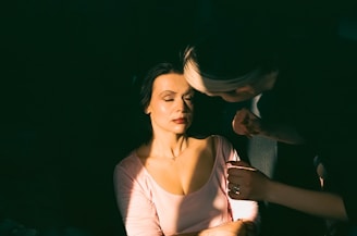 Soft lighting showing a beautician carefully applying eyelash tint.