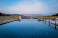 A luxury resort’s infinity pool reflecting the clear blue sky and distant Himalayan ranges.