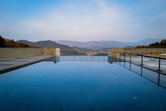 A luxury resort’s infinity pool reflecting the clear blue sky and distant Himalayan ranges.