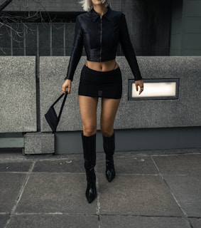 a woman in a short skirt and boots walking down the street