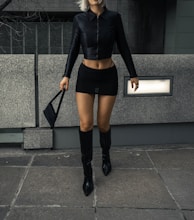 a woman in a short skirt and boots walking down the street