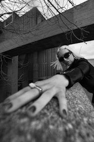 a woman in sunglasses leaning on a rock