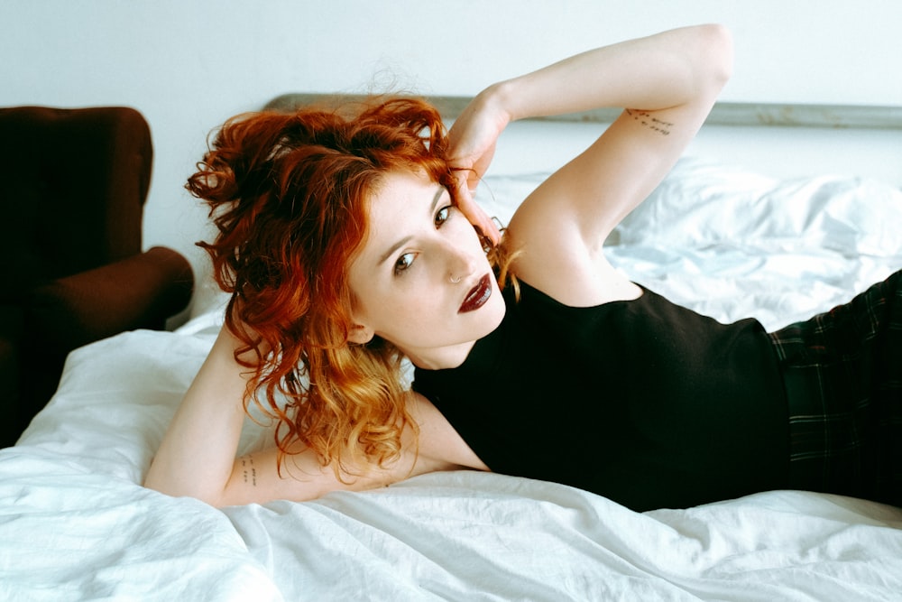 a woman with red hair laying on a bed