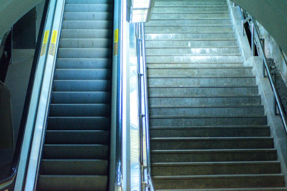 an escalator leading up to the top of a flight of stairs