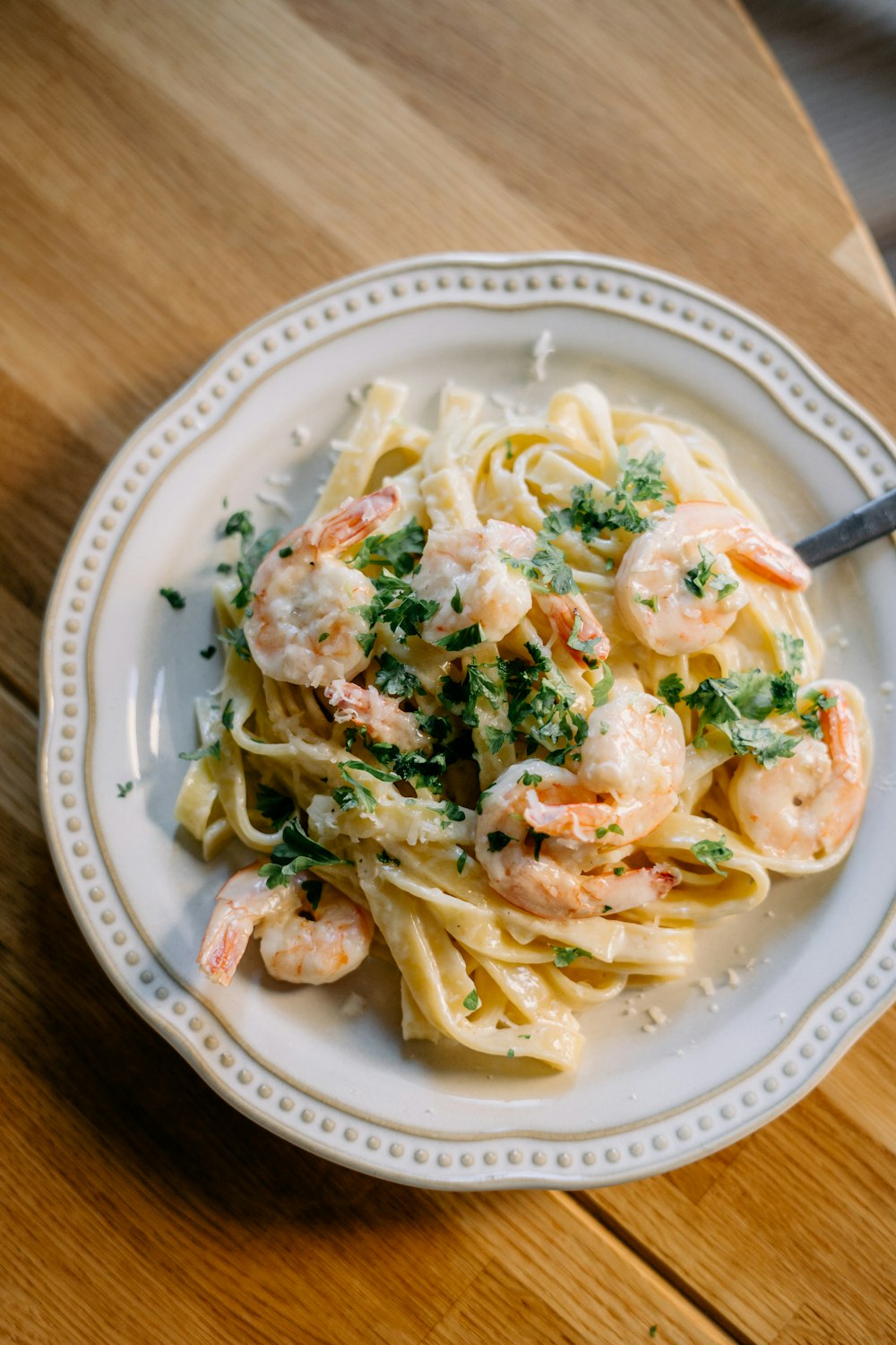 a plate of pasta with shrimp and parsley