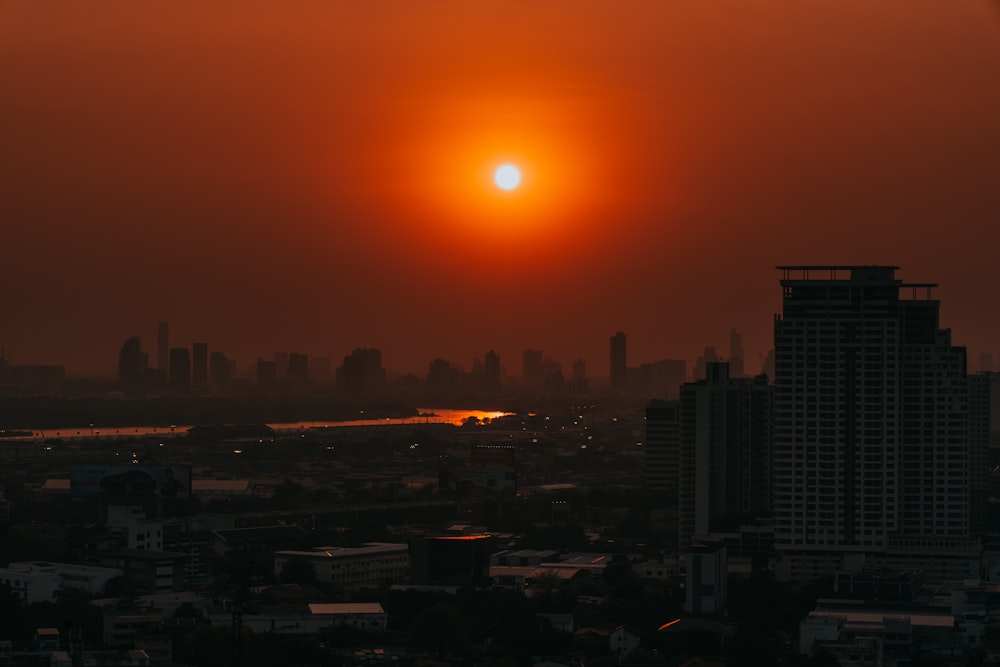 the sun is setting over a city with tall buildings