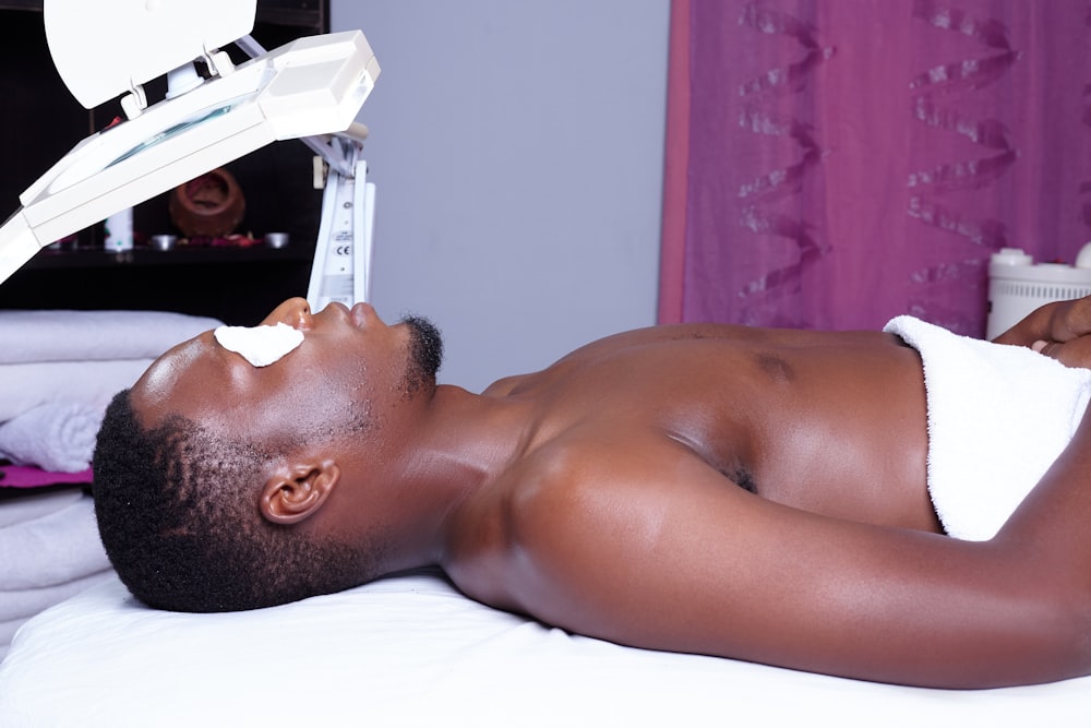 a man laying on top of a bed next to a machine