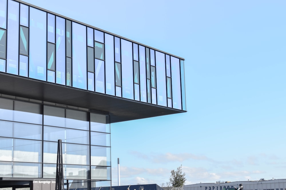 a tall building with a glass front and a sky background