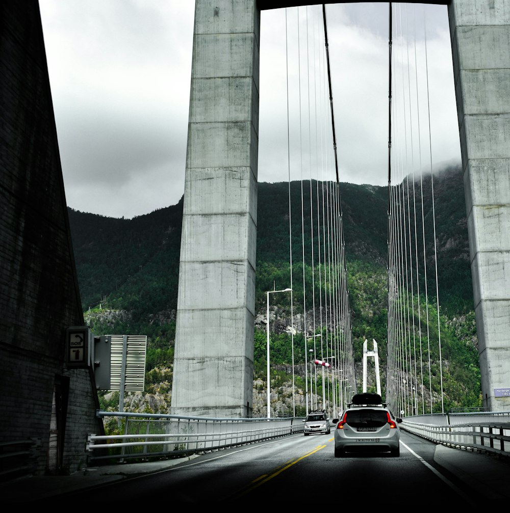 a car driving across a bridge with mountains in the background