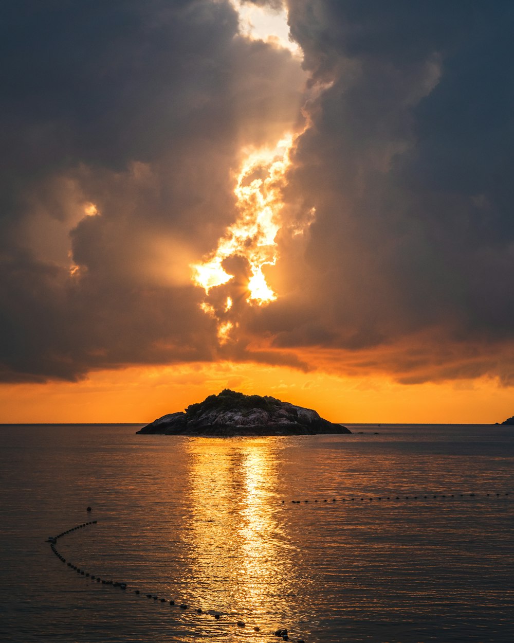 the sun is setting over a small island in the middle of the ocean