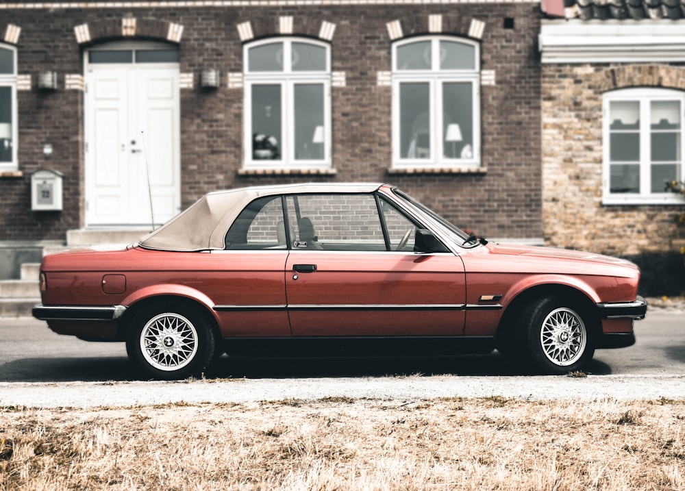 a red car parked in front of a brick building