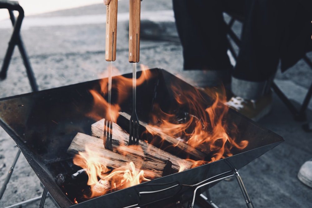 a person cooking food over a fire with tongs