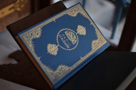 A beautifully designed journal with inspirational Islamic quotes on the cover, resting on a wooden desk.