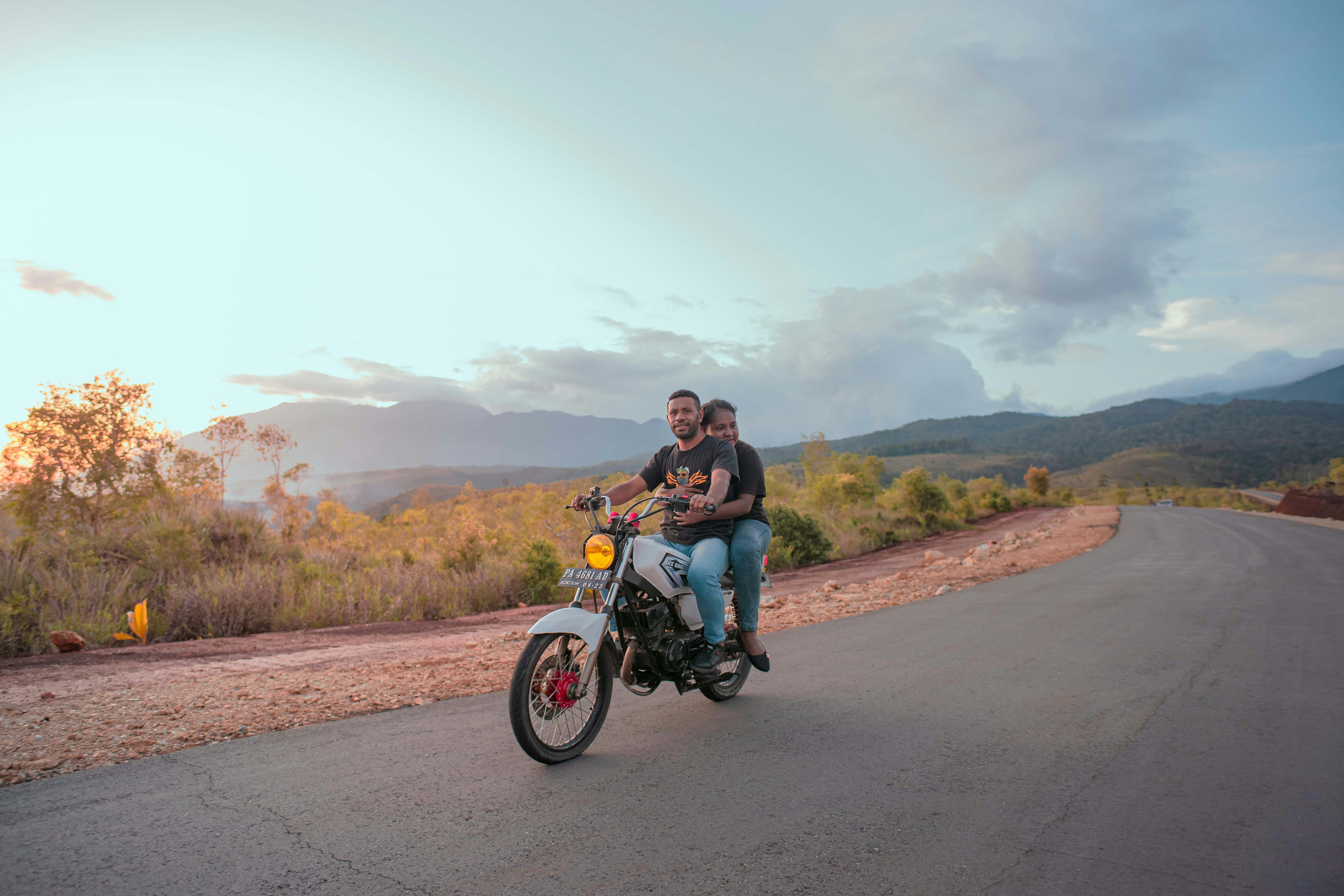 two people riding a motorcycle on a road