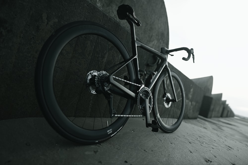 Una foto en blanco y negro de una bicicleta apoyada contra una pared