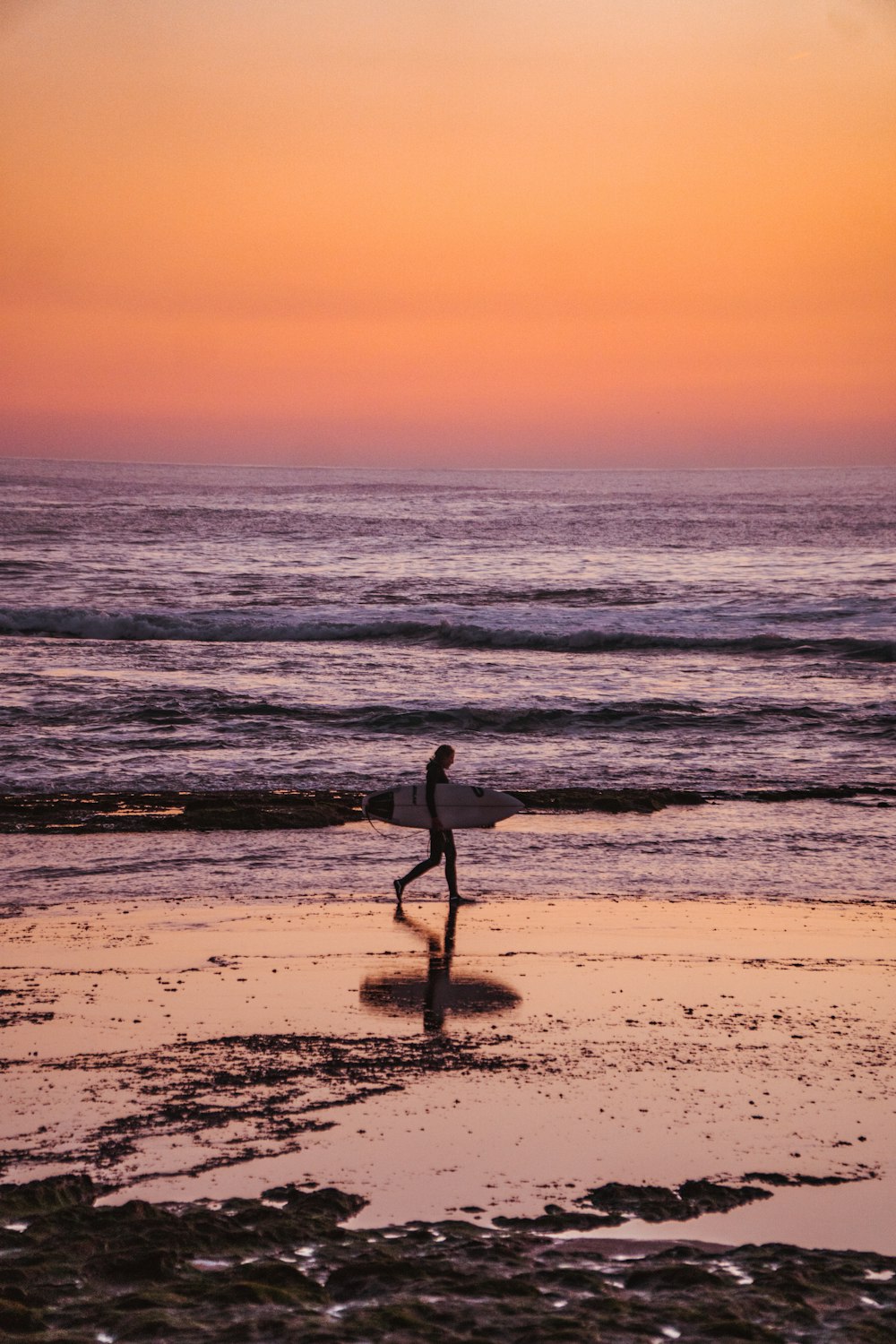 a person walking on the beach with a surfboard