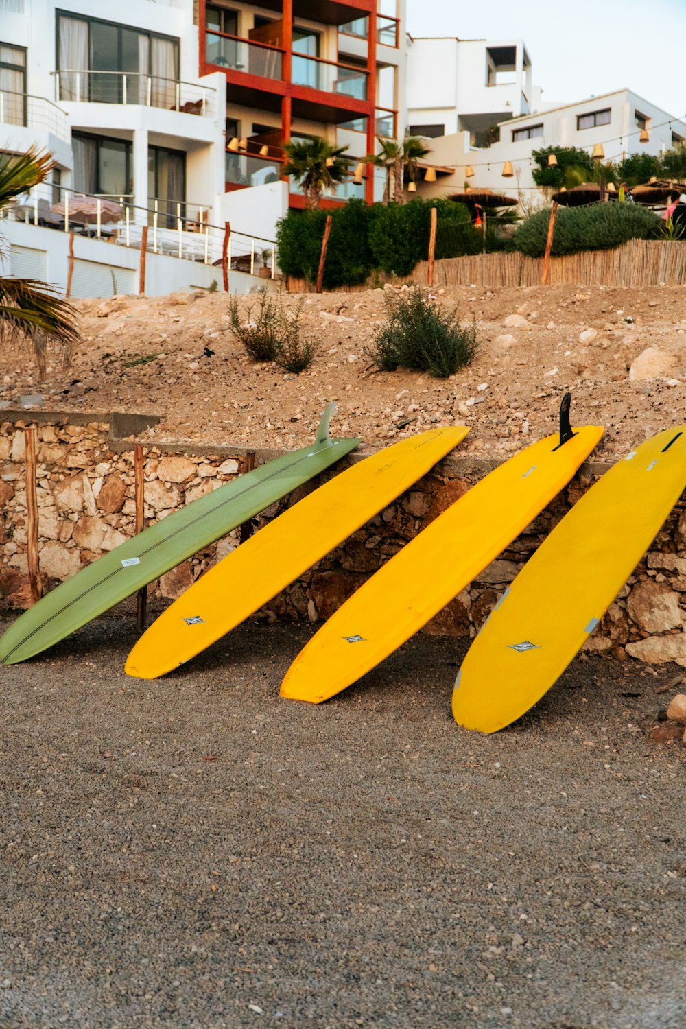 three surfboards leaning against a stone wall