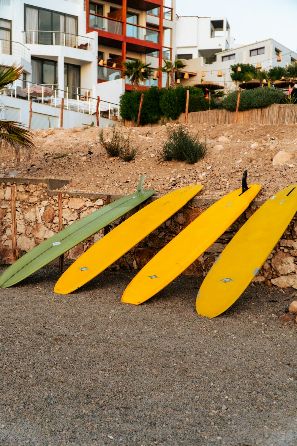 Trois planches de surf appuyées contre un mur de pierre