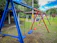 Children laughing and swinging joyfully on colorful playground swings under a bright sky.
