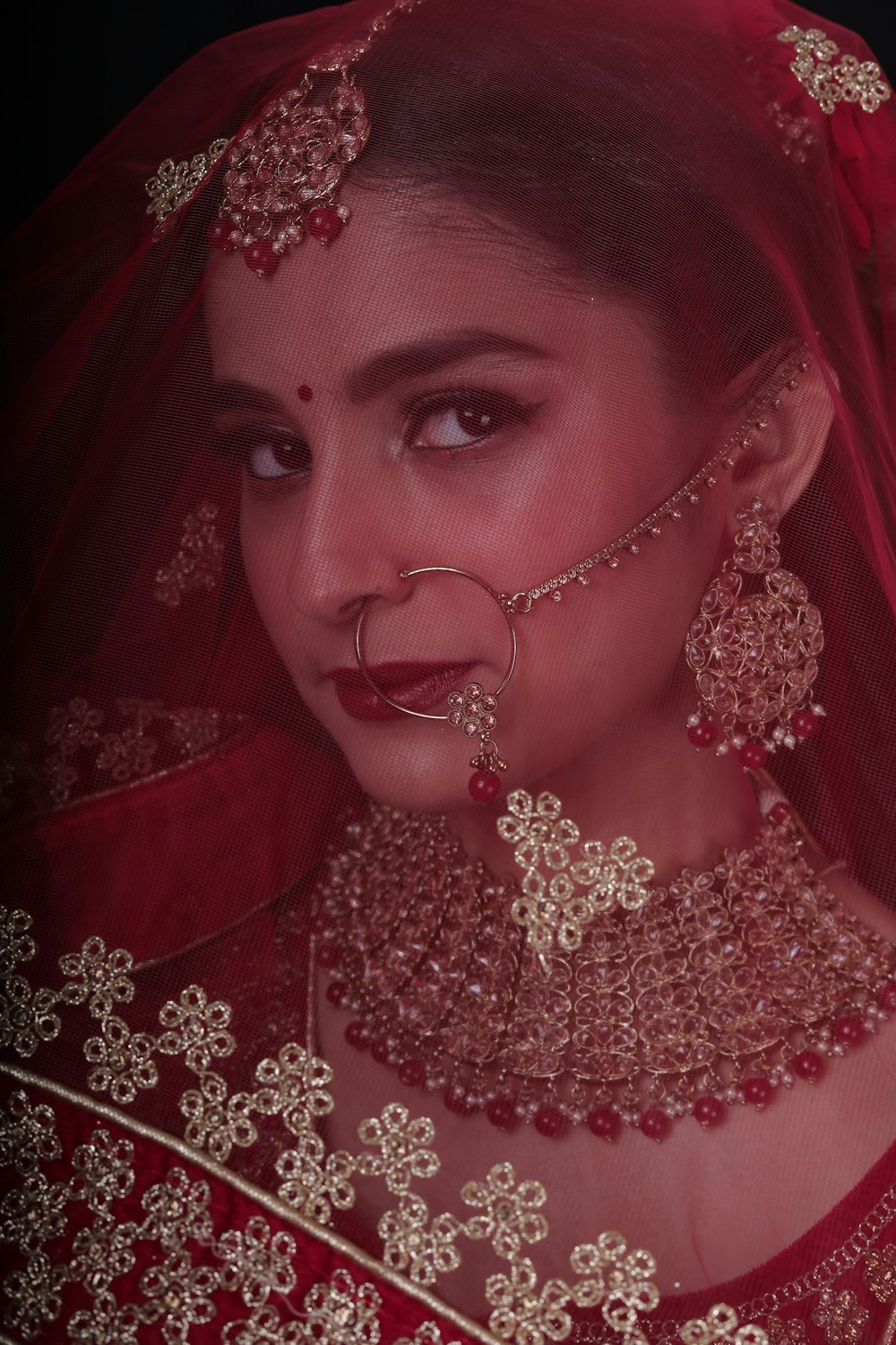 a woman wearing a red veil and jewelry