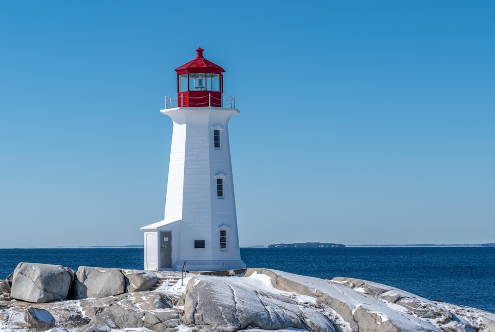 a white and red light house sitting on top of a rock