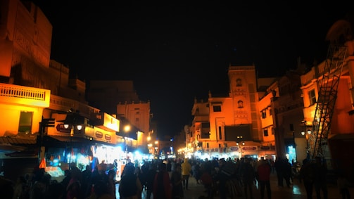 Nighttime street scene with colorful lights and bustling crowds in a Singapore market.