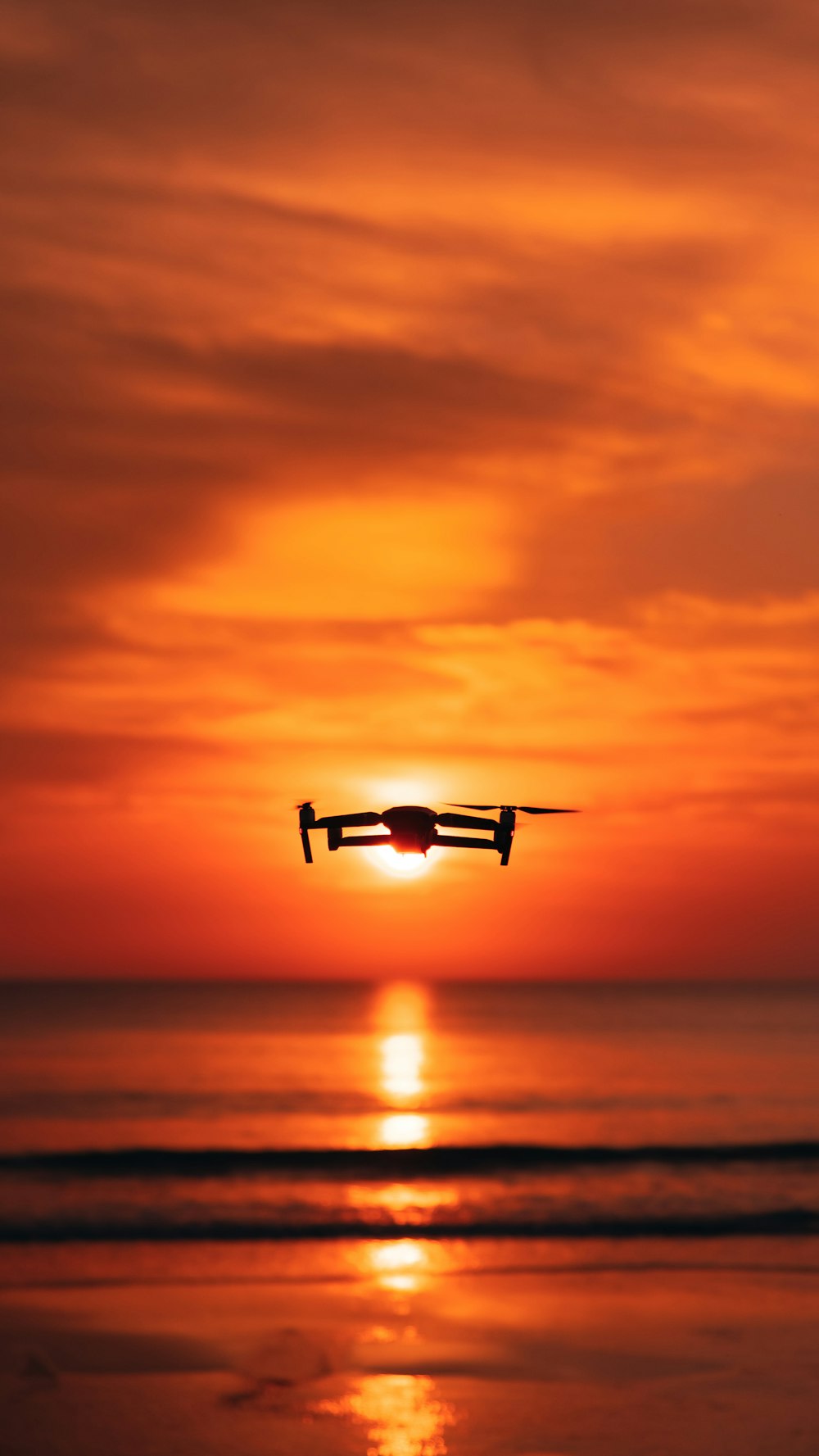 a plane flying over the ocean at sunset