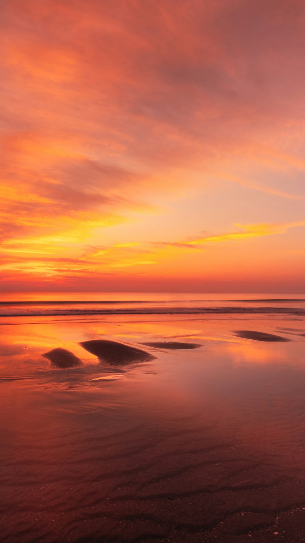 a beautiful sunset over the ocean with waves coming in