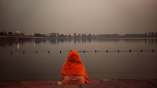 Person sitting in silent meditation by still water - Vipassana practice