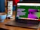 A laptop displaying a website about language models is set on a wooden table. A coffee cup is nearby, next to a menu stand featuring a beef dish advertisement.