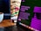A laptop displays a screen with the title 'ChatGPT: Optimizing Language Models for Dialogue', accompanied by descriptive text. The background shows a blurred image of a sandwich, and there's a white cup on the wooden table next to the laptop.