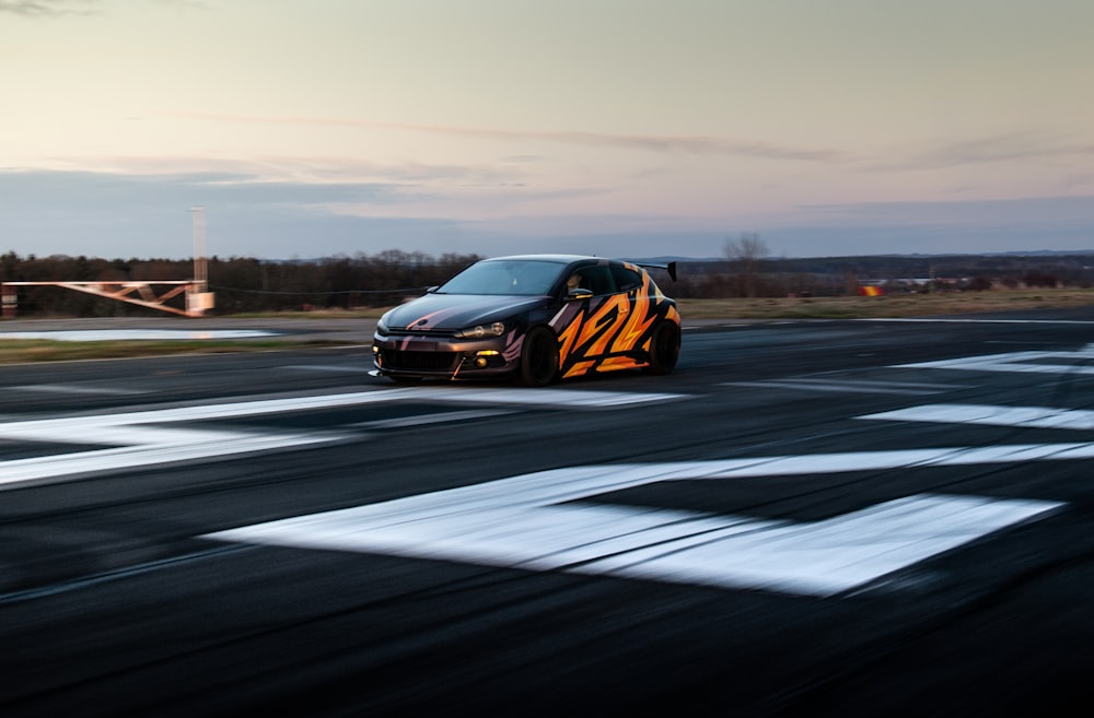 a black car driving down a race track