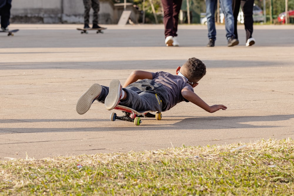 a young boy laying on his stomach on a skateboard