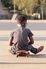 a young boy sitting on top of a skateboard