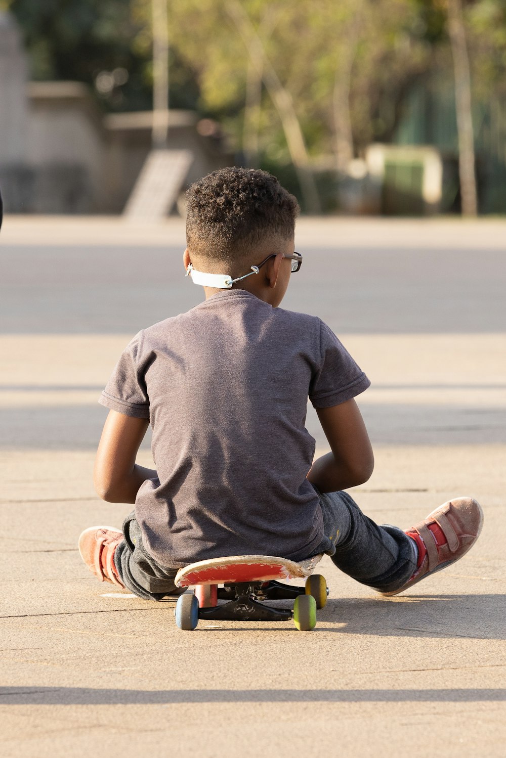 a young boy sitting on top of a skateboard