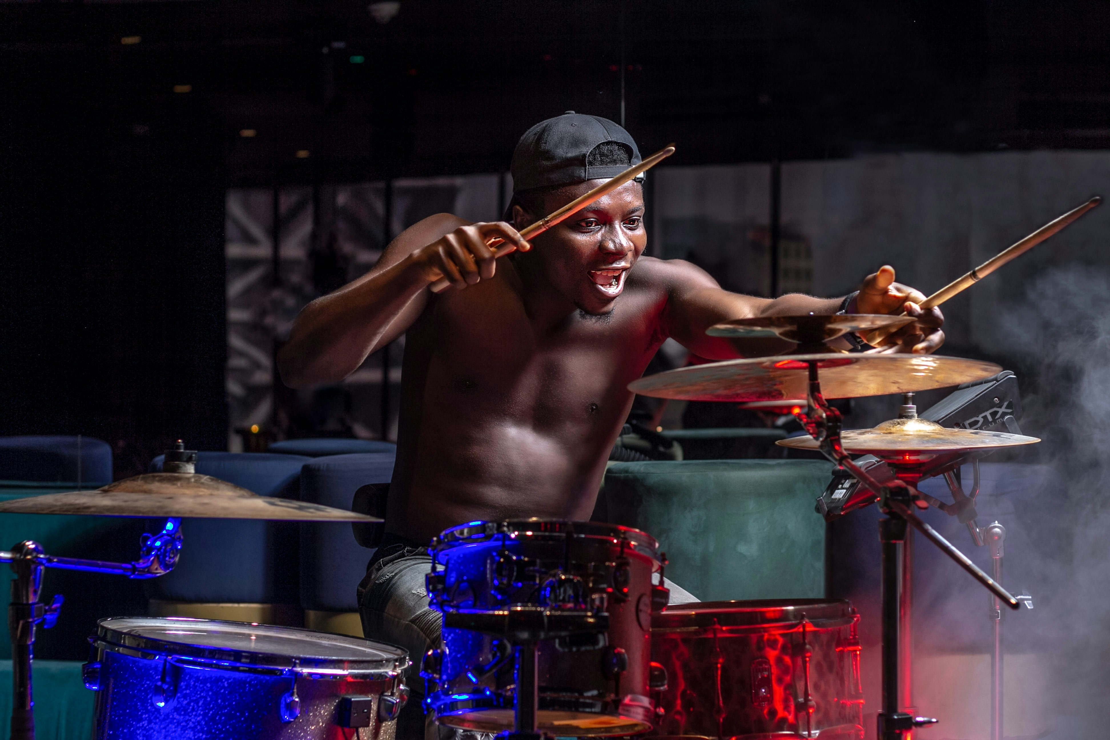 a shirtless man playing drums on stage