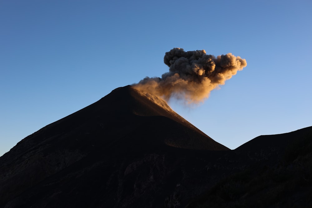 a large plume of smoke rising from the top of a mountain