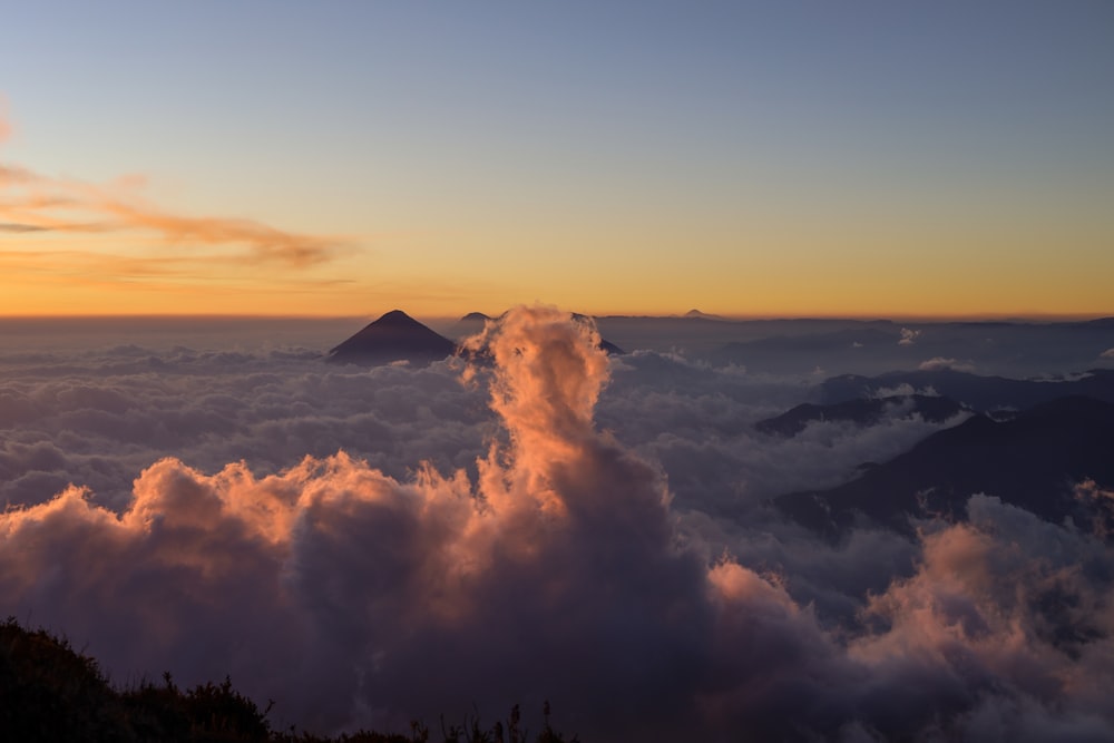 a mountain in the distance with a cloud in the foreground